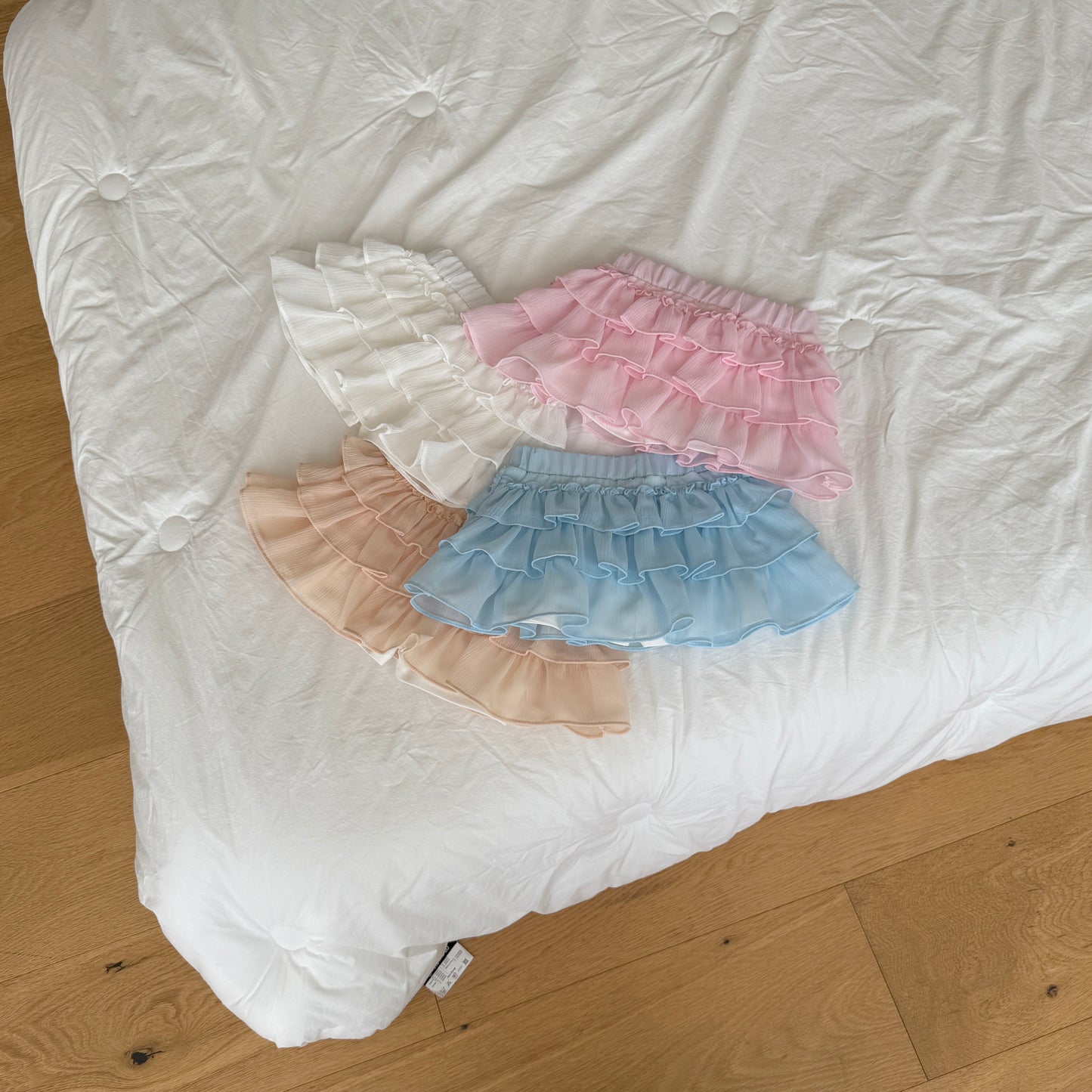 Four ruffled pet skirts in pink, blue, and beige