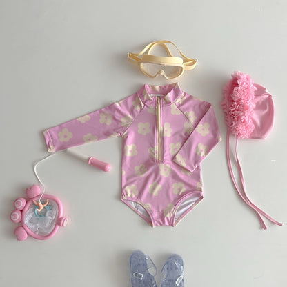 Pink children's swimsuit with floral pattern, goggles, hat, and accessories on a light gray background