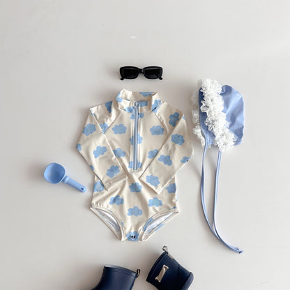 Children's swimsuit with cloud pattern, sunglasses, and accessories on a light gray background