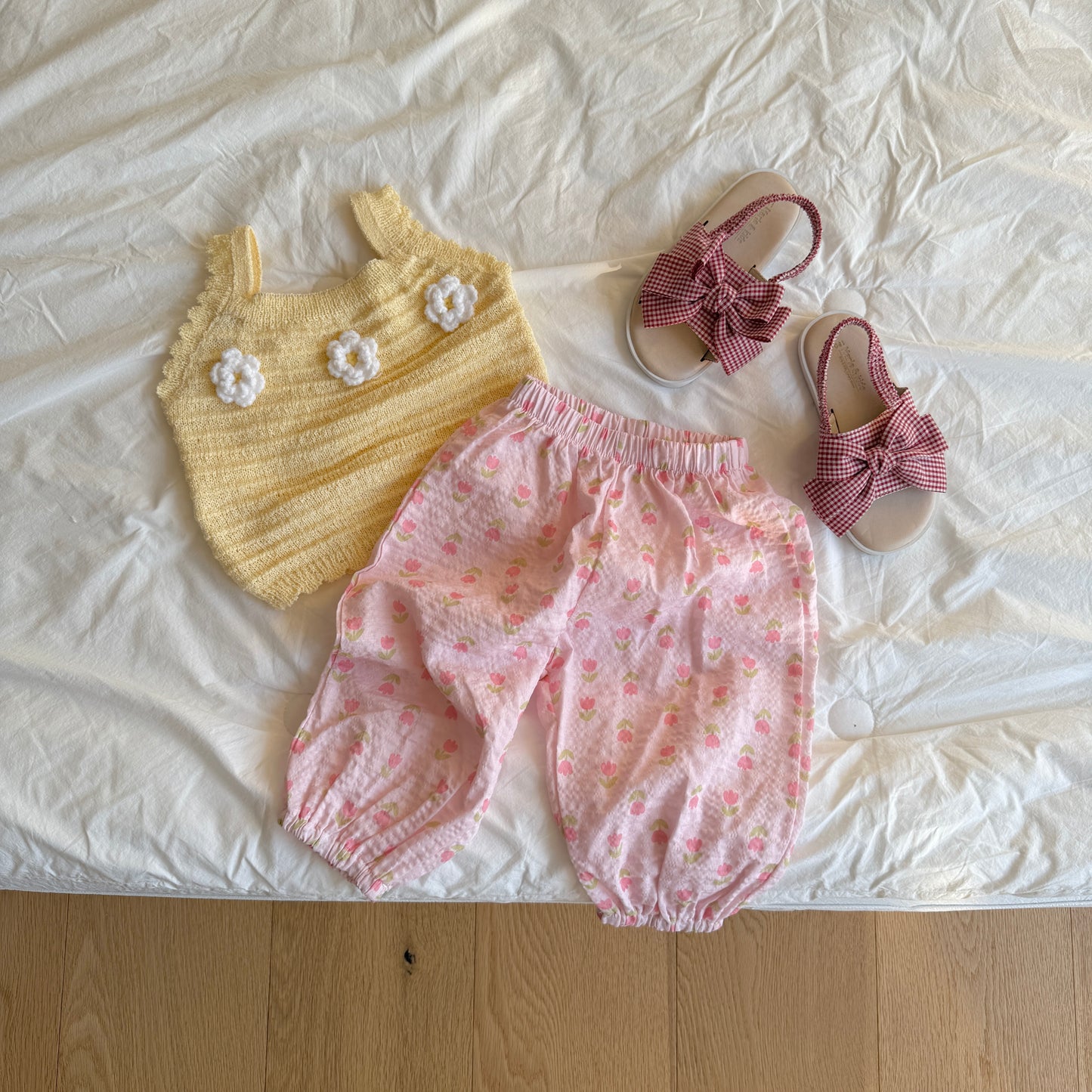 Baby outfit with yellow top and pink bloomers on a white surface.